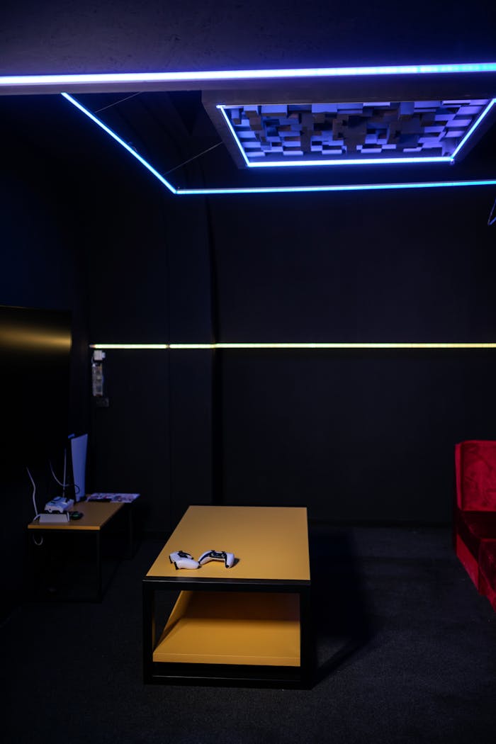 A sleek gaming room featuring a table with controllers and ambient neon lighting.